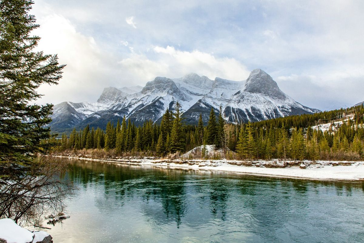 A calm river below snow-capped mountains in the Canadian Rockies