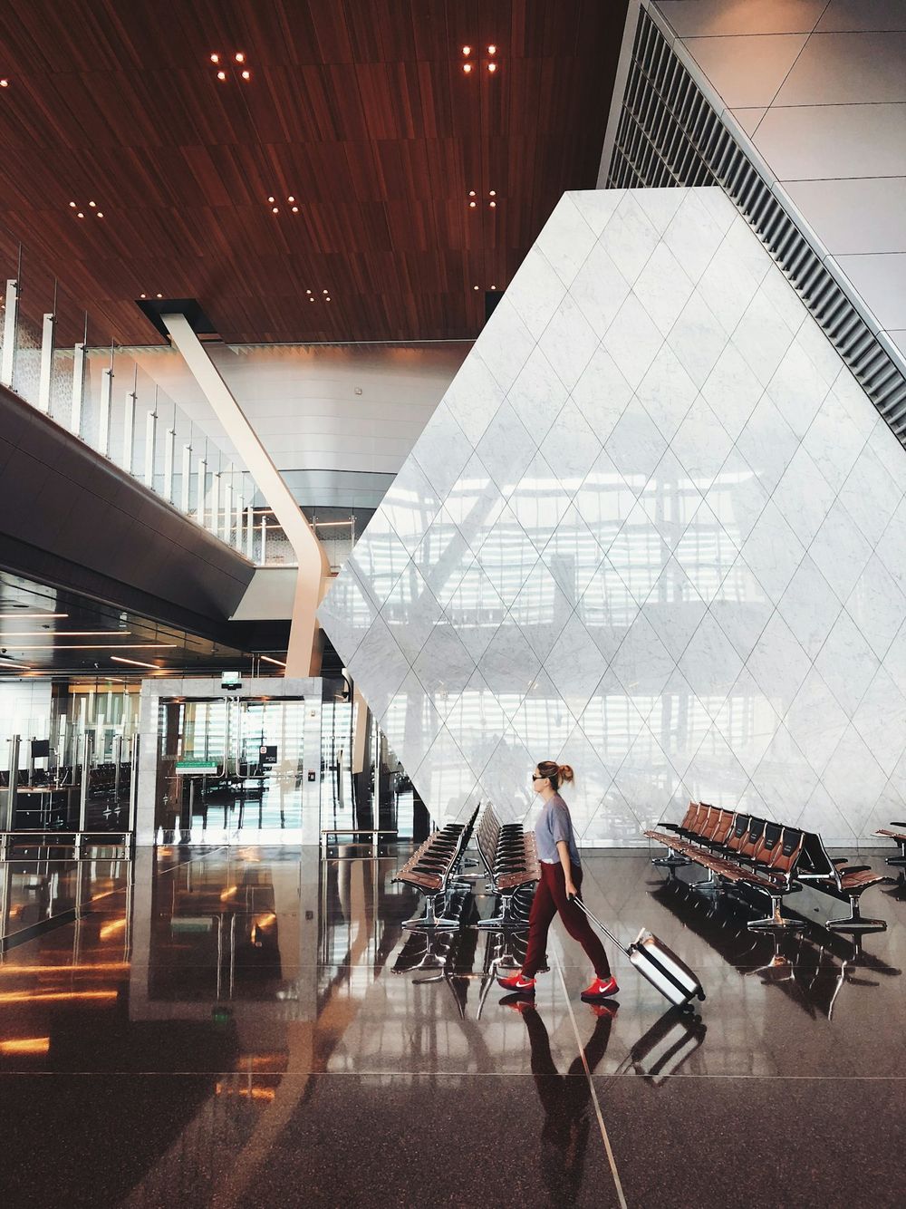 A traveler with a suitcase walking through a bright airport terminal