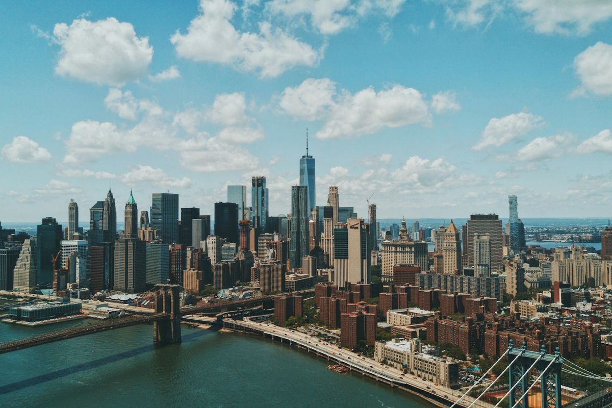 Aerial view of the Manhattan skyline and Brooklyn Bridge under a bright sky
